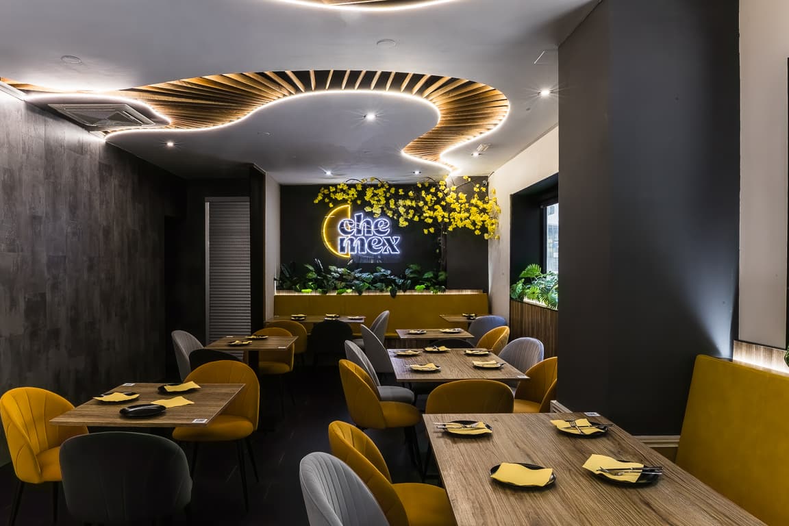 Interior del restaurante Chemex con mesas preparadas y sillas amarillas