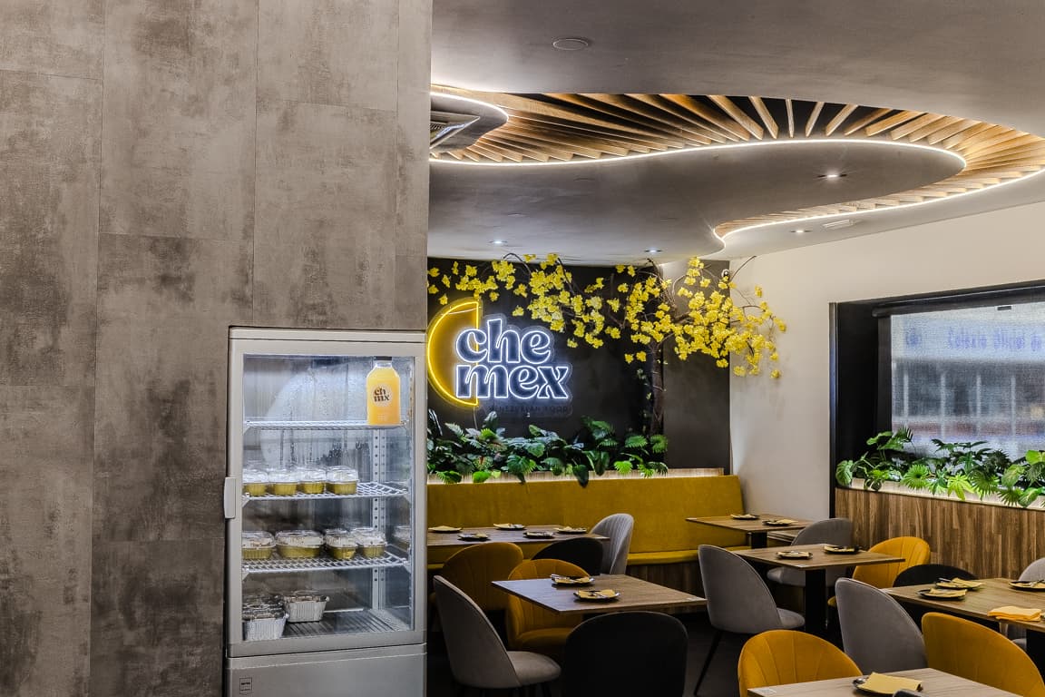 Salón de Chemex con la vitrina refrigerada, el letrero iluminado y mesas